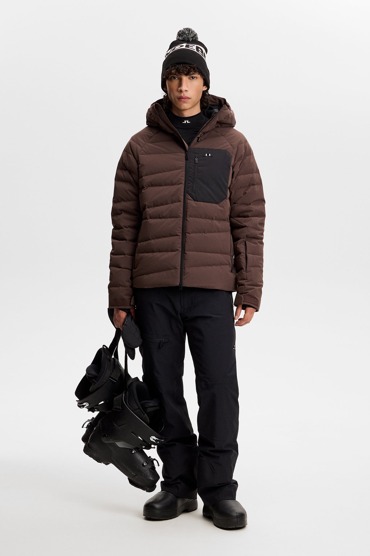 Front view: Model wearing the Thornton Down Jacket in Seal Brown with quilted panels and a contrast chest pocket.