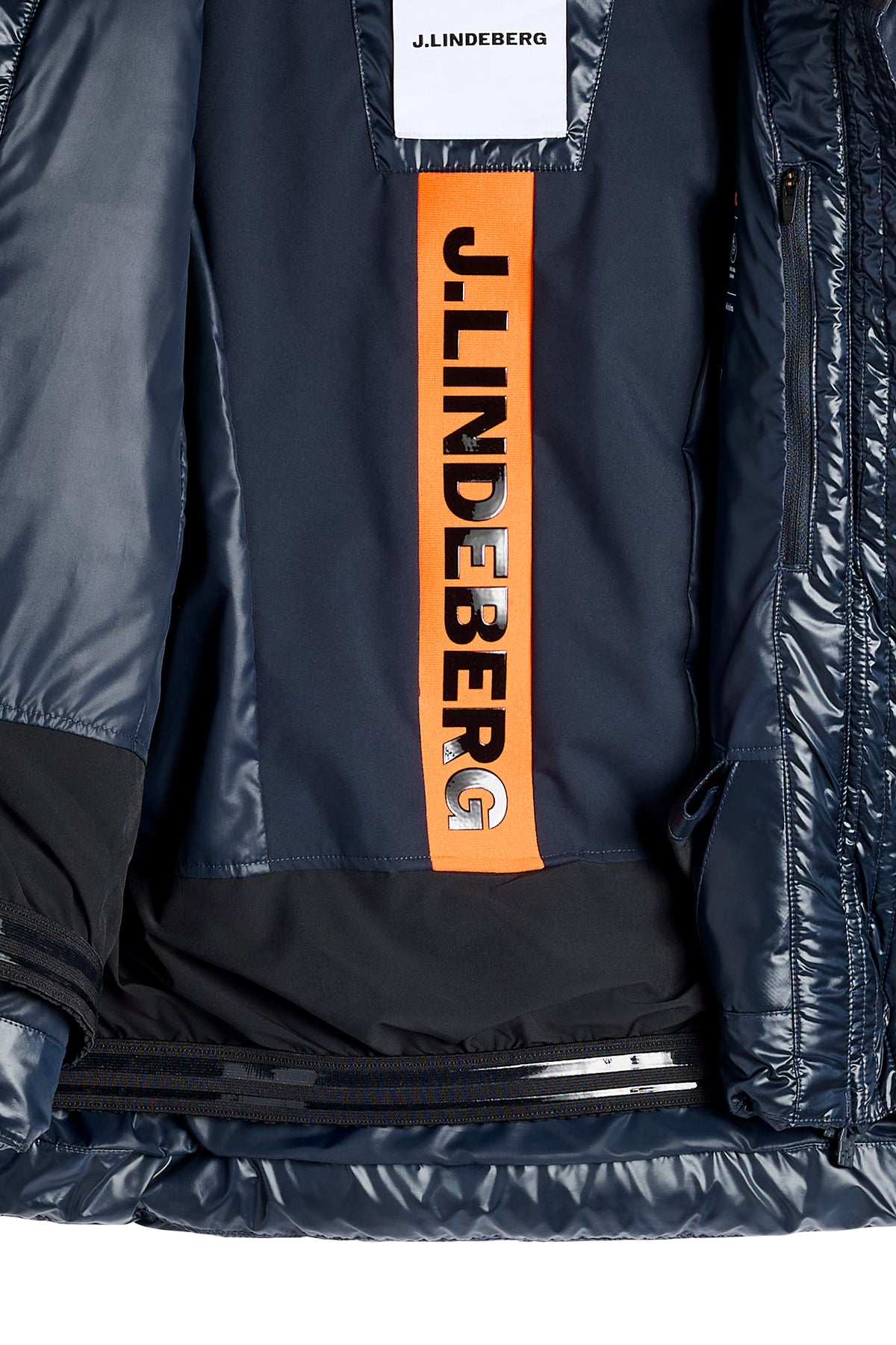 Detailansicht: Innenseite der Nerina Down Jacket in JL Navy mit orangefarbenem J.LINDEBERG-Schriftzug und Schneefang.