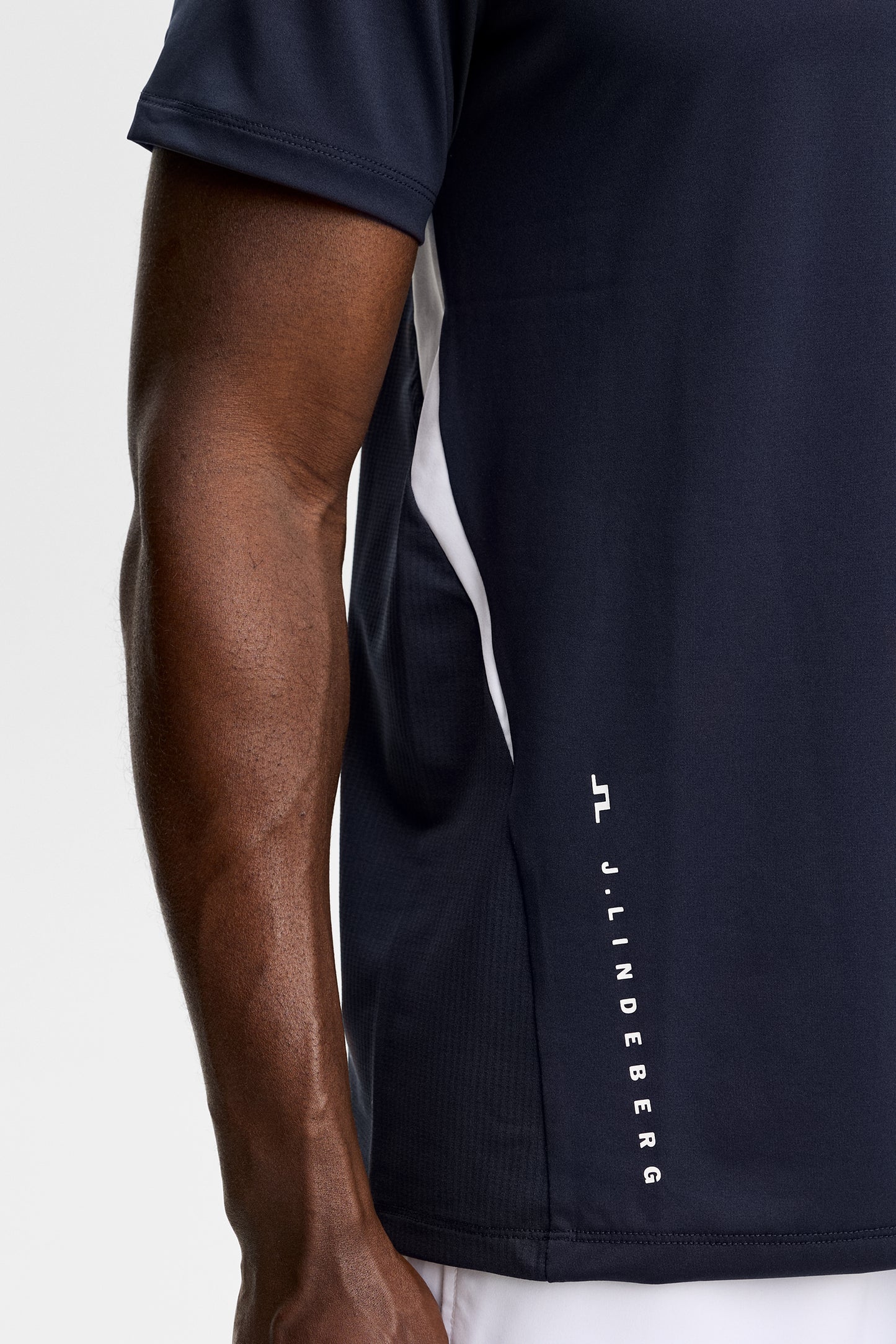 Nærbillede fra siden: Dennis T-shirt i JL Navy med hvidt kontrastpanel, mesh-side og lodret J.Lindeberg-logo.